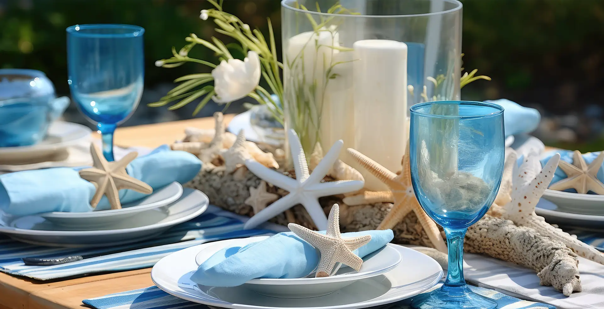 A seaside-themed dining table set with starfish, blue glasses, and candles.