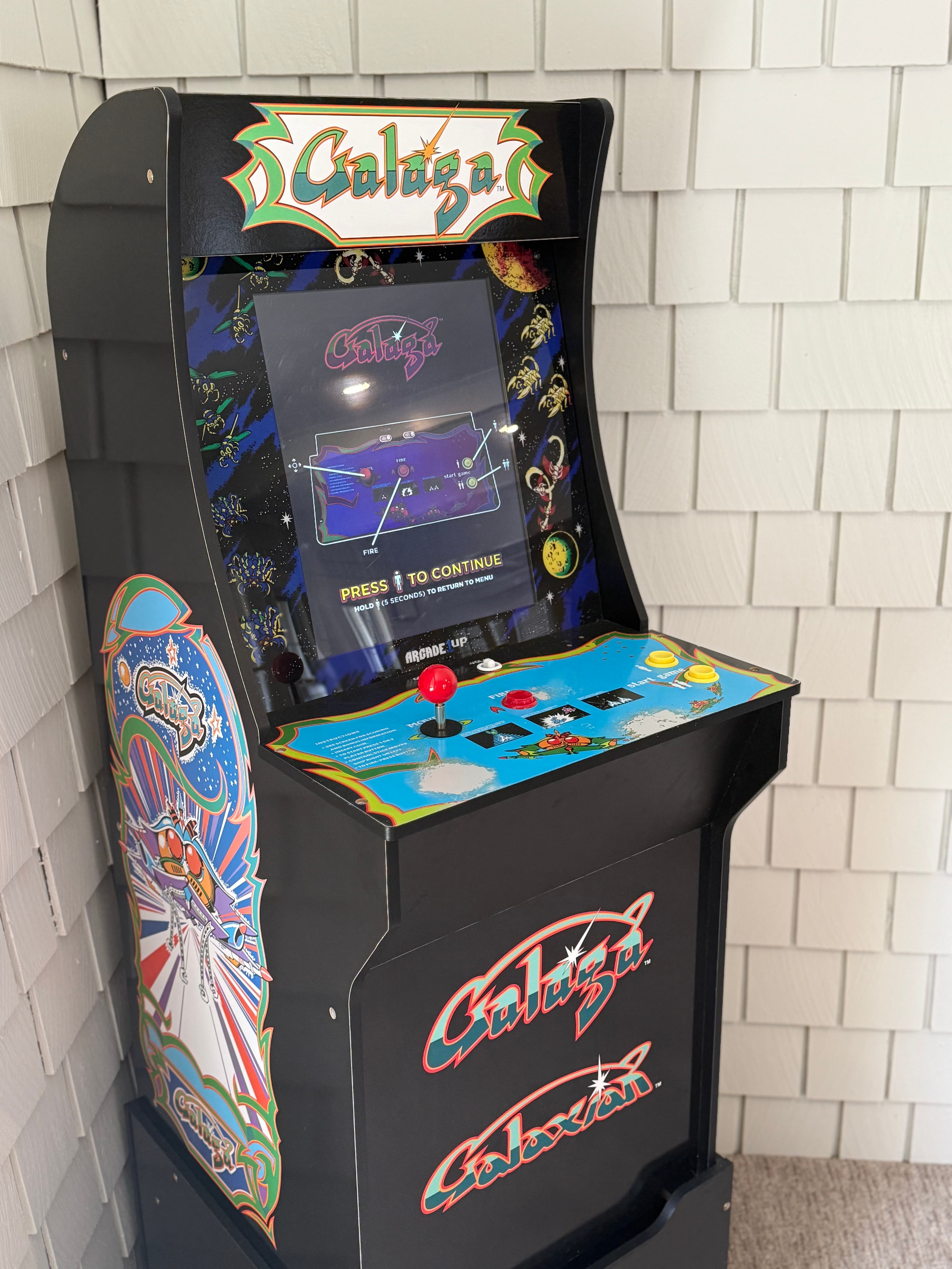 A retro arcade game machine labeled "Galaga" with colorful graphics and a start screen.