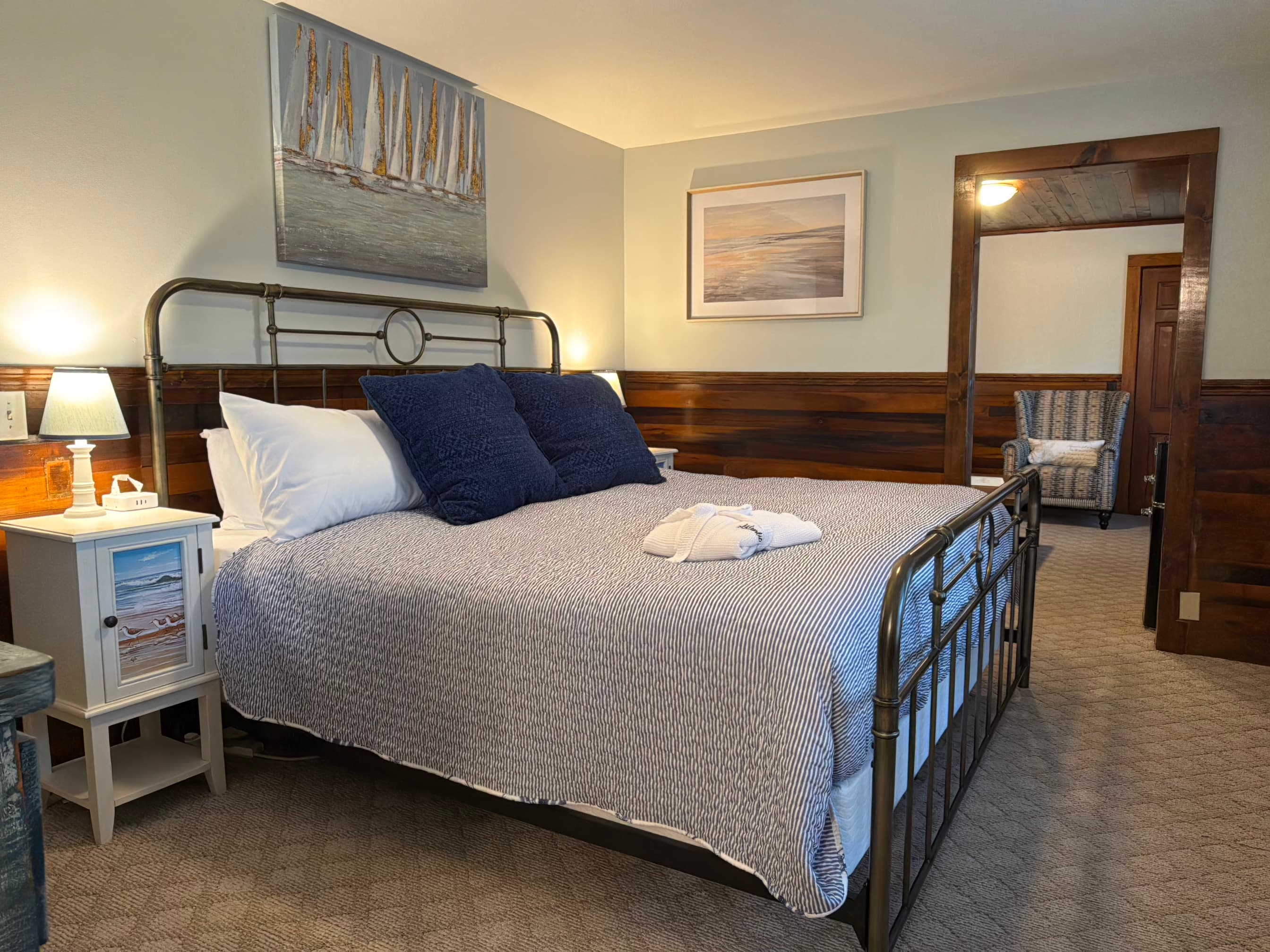 Cozy bedroom featuring a metal-framed bed, plush pillows, and nautical-themed artwork.