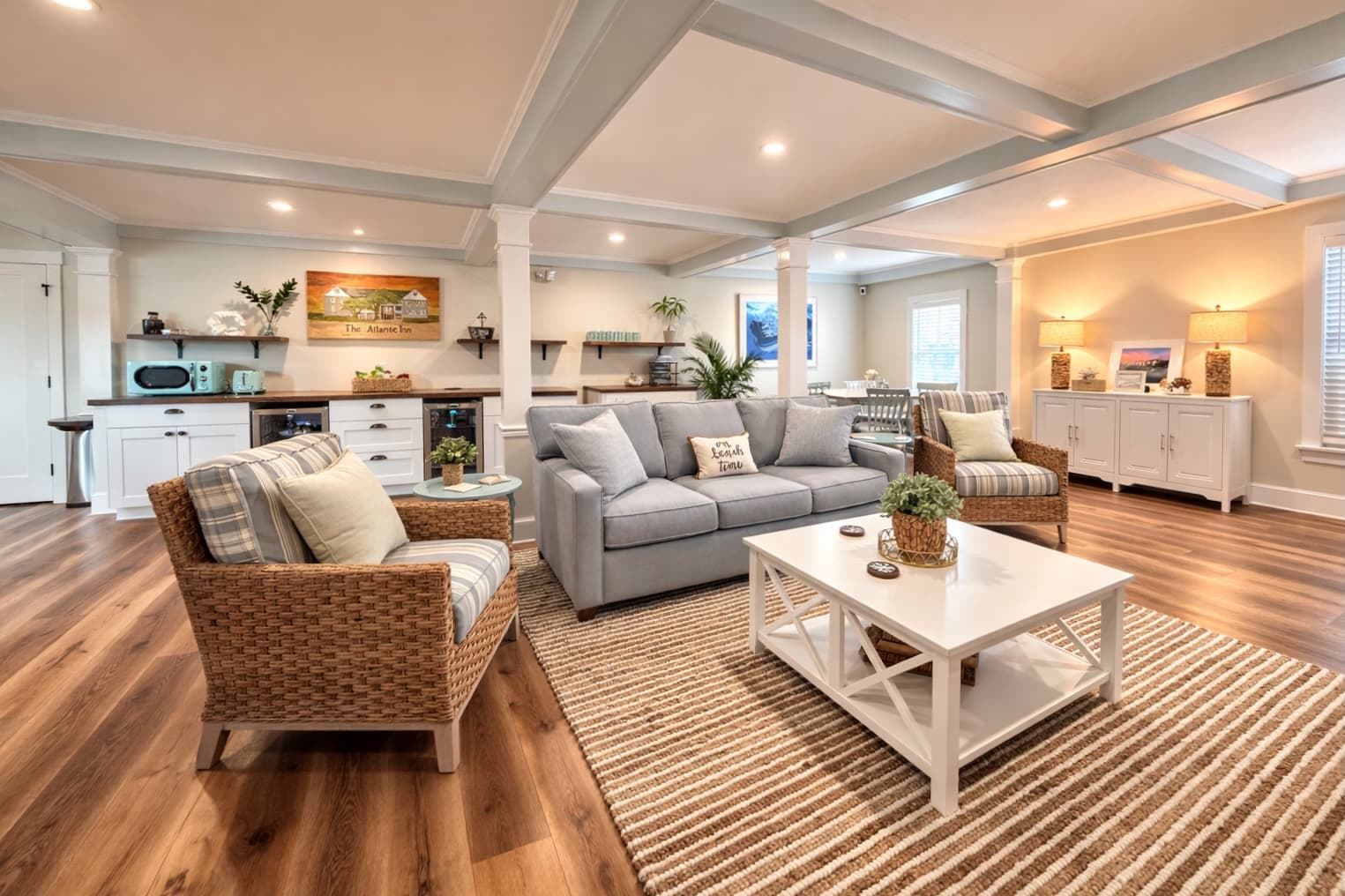 A cozy, modern living room with a grey sofa, wicker chairs, and a coffee table, featuring hardwood floors and warm lighting.