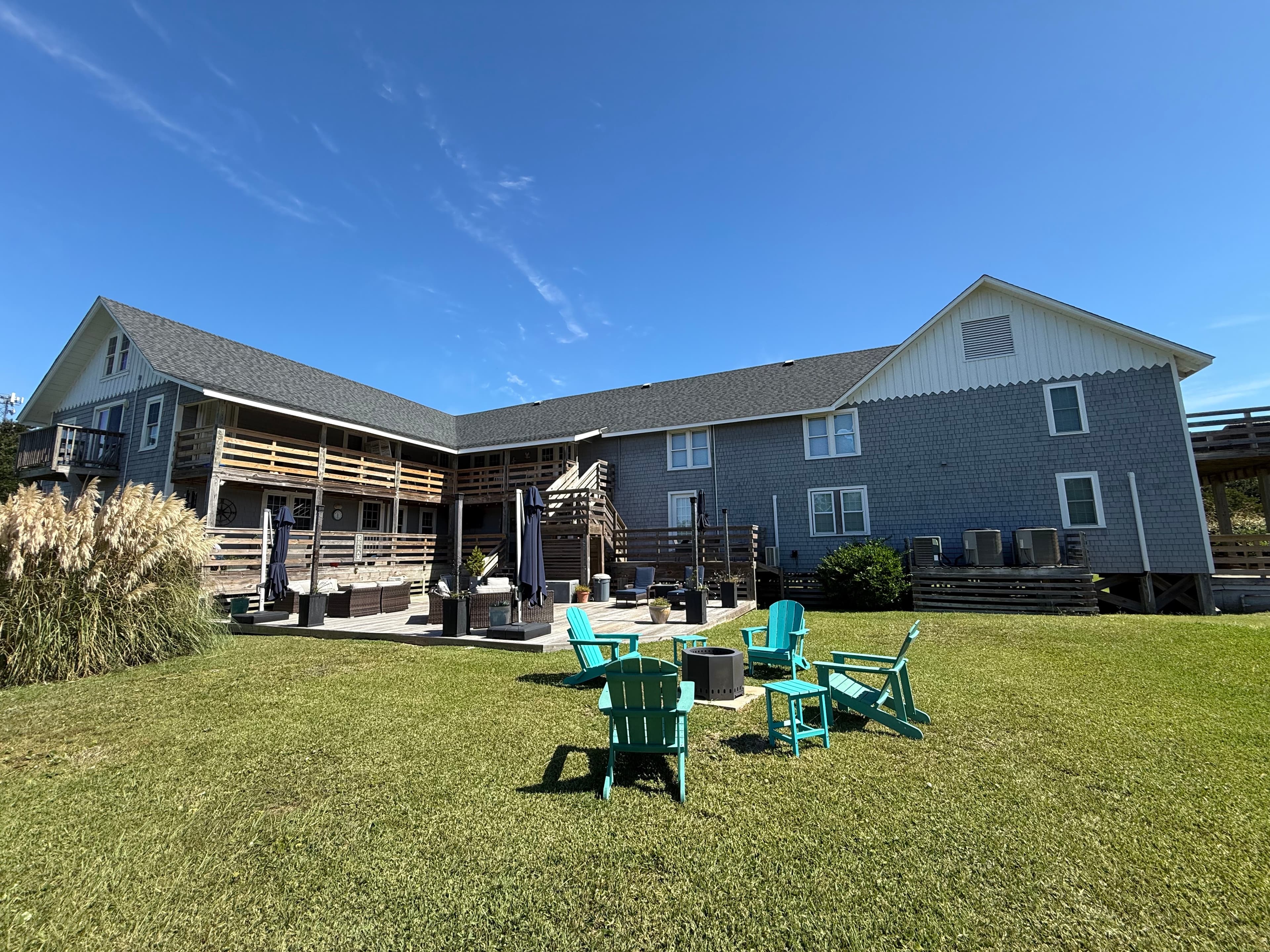 A spacious gray building with outdoor seating on a grassy area under a clear blue sky.